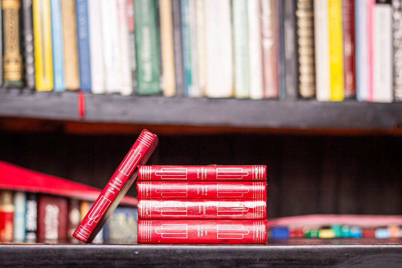 Stack of red books with a bookshelf background, ideal for library themes.