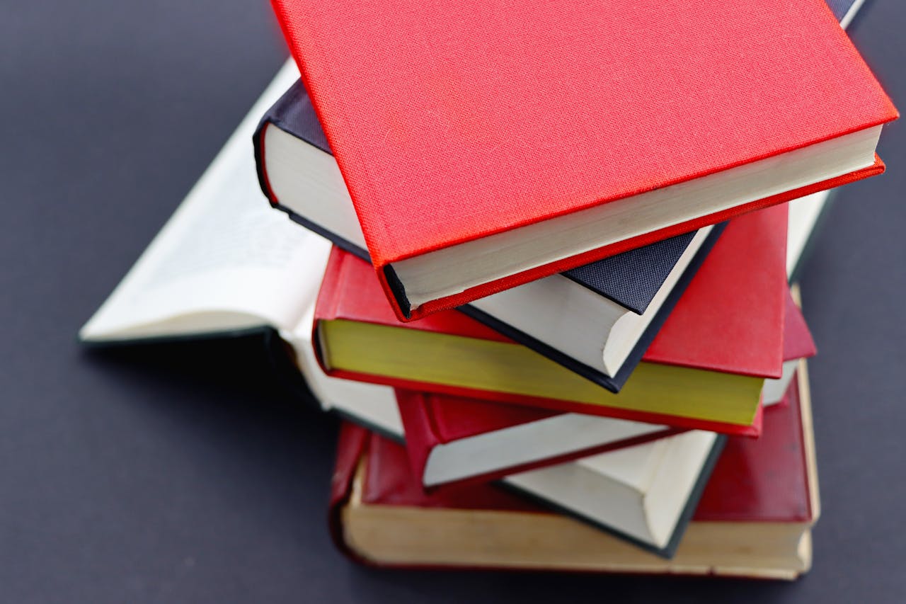 why-choose-us Pile of assorted hardcover books with colorful covers, perfect for study or literature themes.